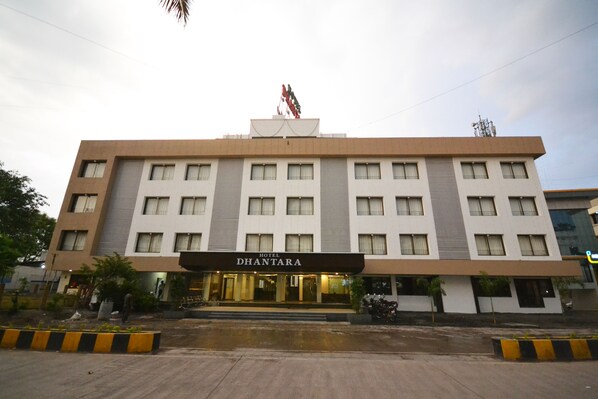 Un hotel llamado "DHANTARA" con una fachada moderna, múltiples ventanas y una entrada destacada.