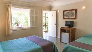 A room with two beds, a TV on a wooden stand, a small fridge, and a window with curtains. - Pousada Tartaruga (Búzios)