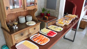 A buffet with various food items and a wooden cabinet with glass jars. - Pousada Tartaruga (Búzios)