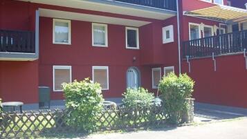 Een rood gebouw met balkons, ramen en een hekwerk.