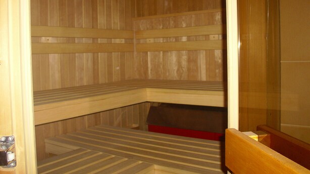A sauna with wooden benches and a clock on the wall.