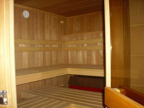 A sauna with wooden benches and a clock on the wall. - Hotel Europa (Holsthum)