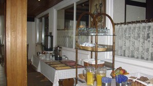 A buffet setup with a variety of food items, including fruits, beverages, and utensils, arranged on tables and shelves.