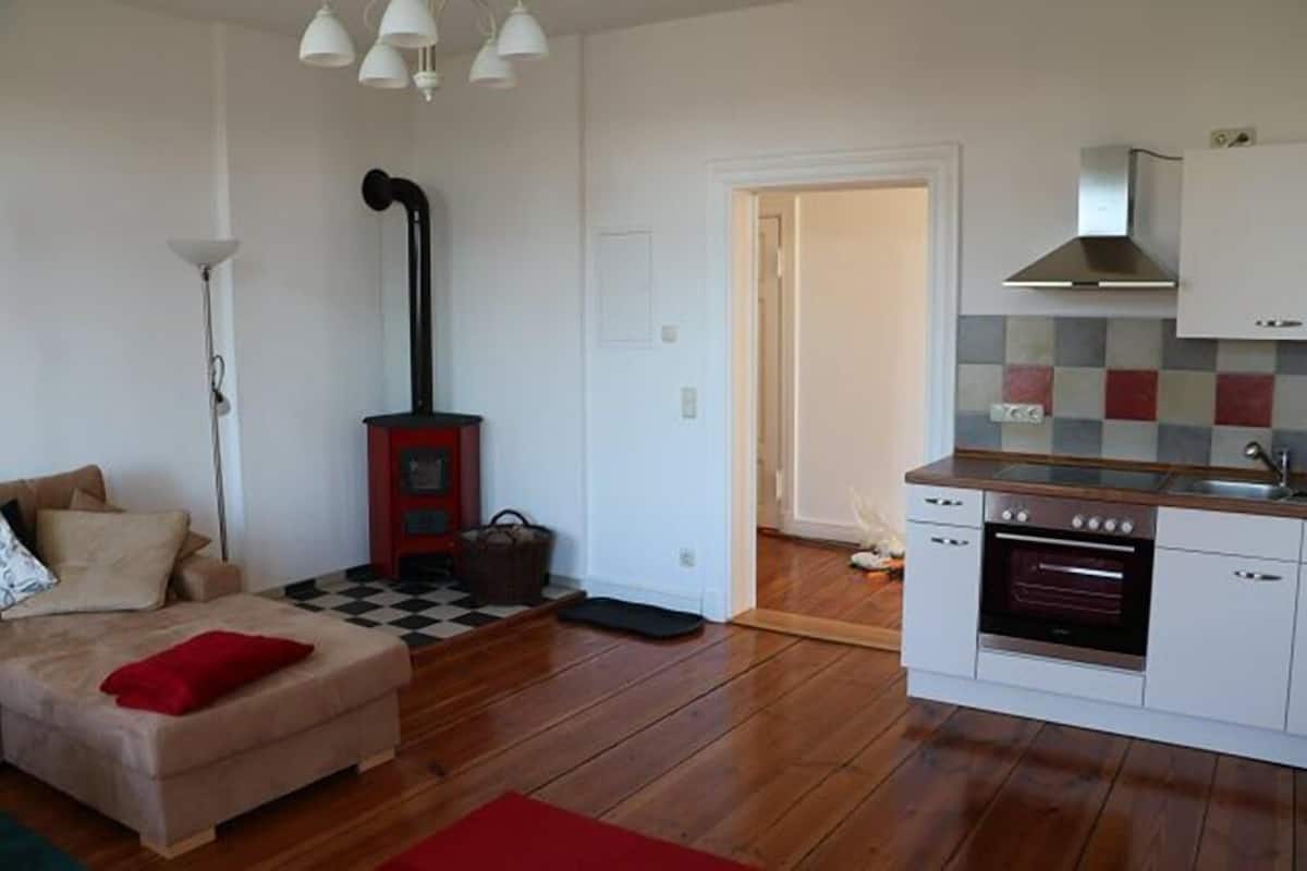 Um espaço compacto com cozinha compacta, sofá, luminária e piso xadrez.