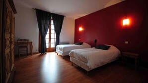 Une chambre avec deux lits, un bureau et une fenêtre avec des rideaux.
