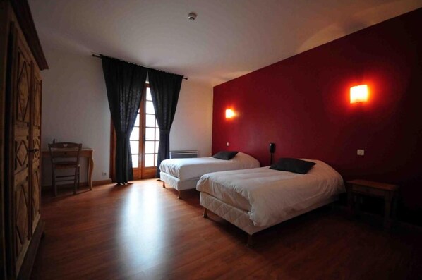 A room with two beds, a desk, and a window with curtains.