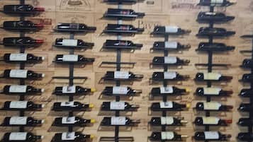 Un mur composé de bouteilles de vin, disposées en rangées sur un fond orné d’étiquettes au style rétro.