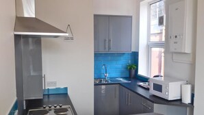 A compact kitchen with a gas stove, a microwave, and a sink. - The Wrens (Leeds)