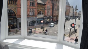 A view from a window overlooking a street with buildings, a bicycle, and a car. - The Wrens (Leeds)