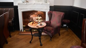 A room with a fireplace, a table with food, and a patterned armchair. - The Wrens (Leeds)