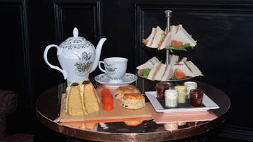 A tea set with sandwiches and scones on a tray.
