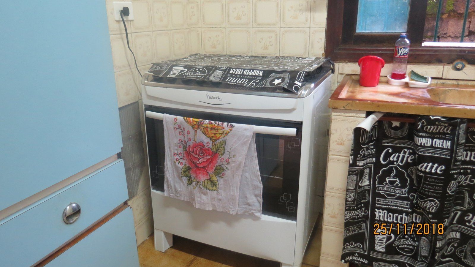 Una cocina con una estufa blanca, una taza roja y una botella de Sprite sobre la encimera.