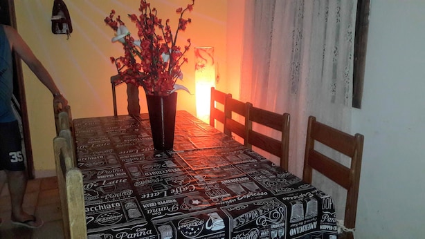 Een eettafel met een tafelkleed met patroon, een vaas met bloemen en houten stoelen.