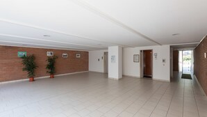 A spacious hallway with a tiled floor, a brick wall on one side, and a white ceiling with recessed lighting.