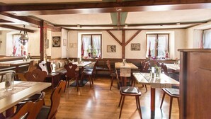 Una posada tradicional con muebles de madera, techo alto con vigas a la vista y amplias ventanas con cortinas.