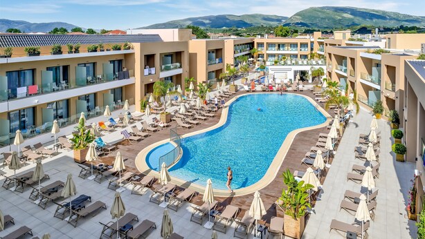 A hotel with a swimming pool, lounge chairs, and a view of mountains. - White Olive Elite Laganas - All Inclusive (Zakynthos)