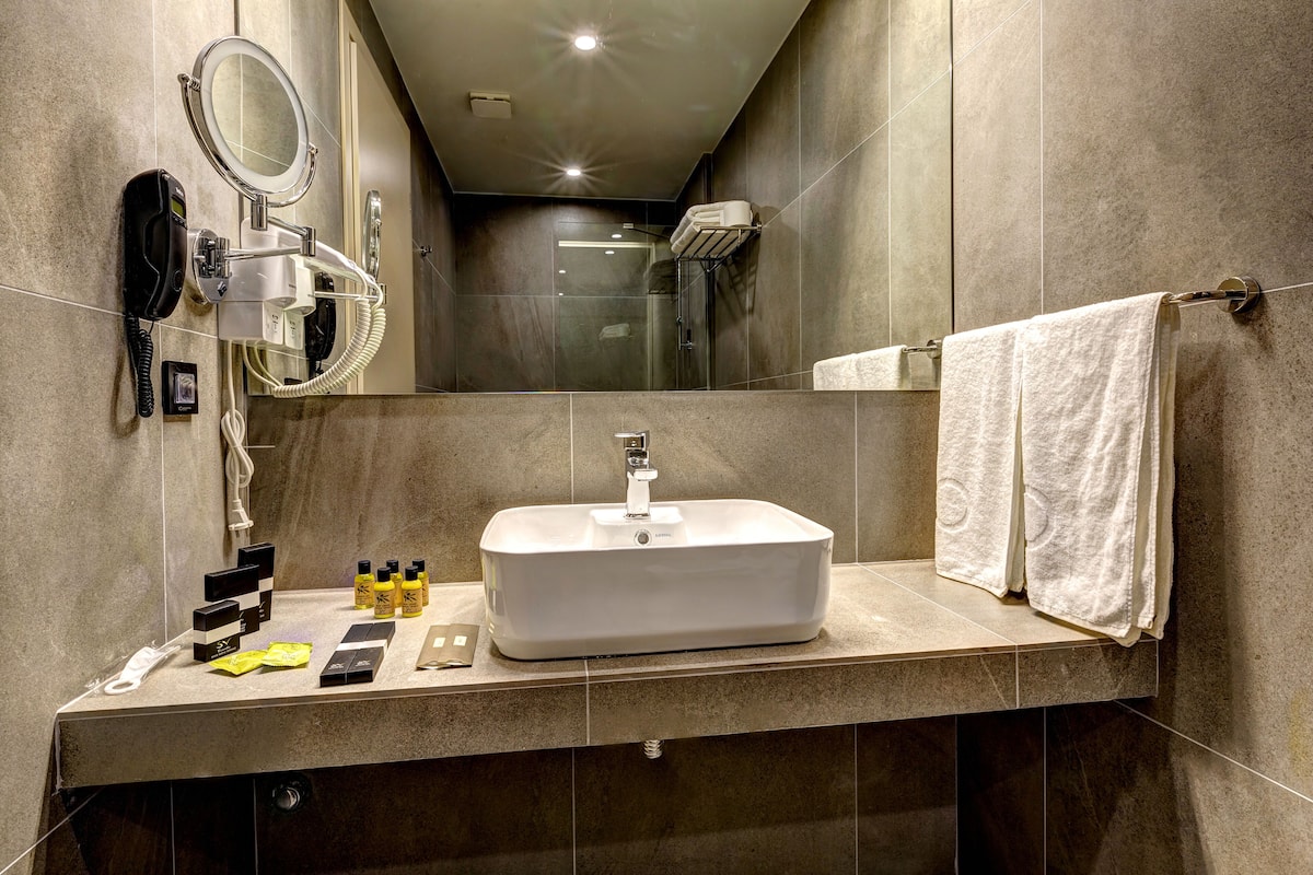Un baño moderno con un espejo grande, un lavabo y un perchero para toallas.