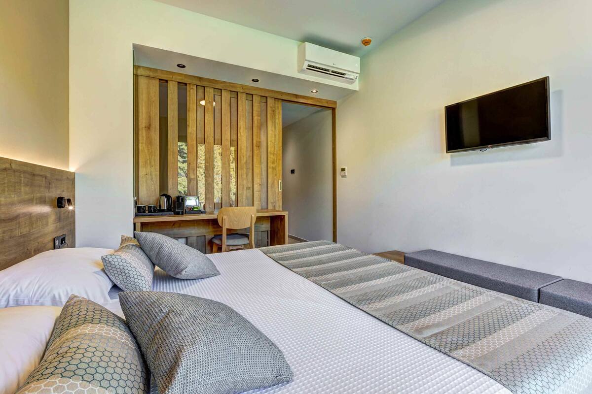 Una habitación de hotel moderna con una cama, un escritorio y un televisor.