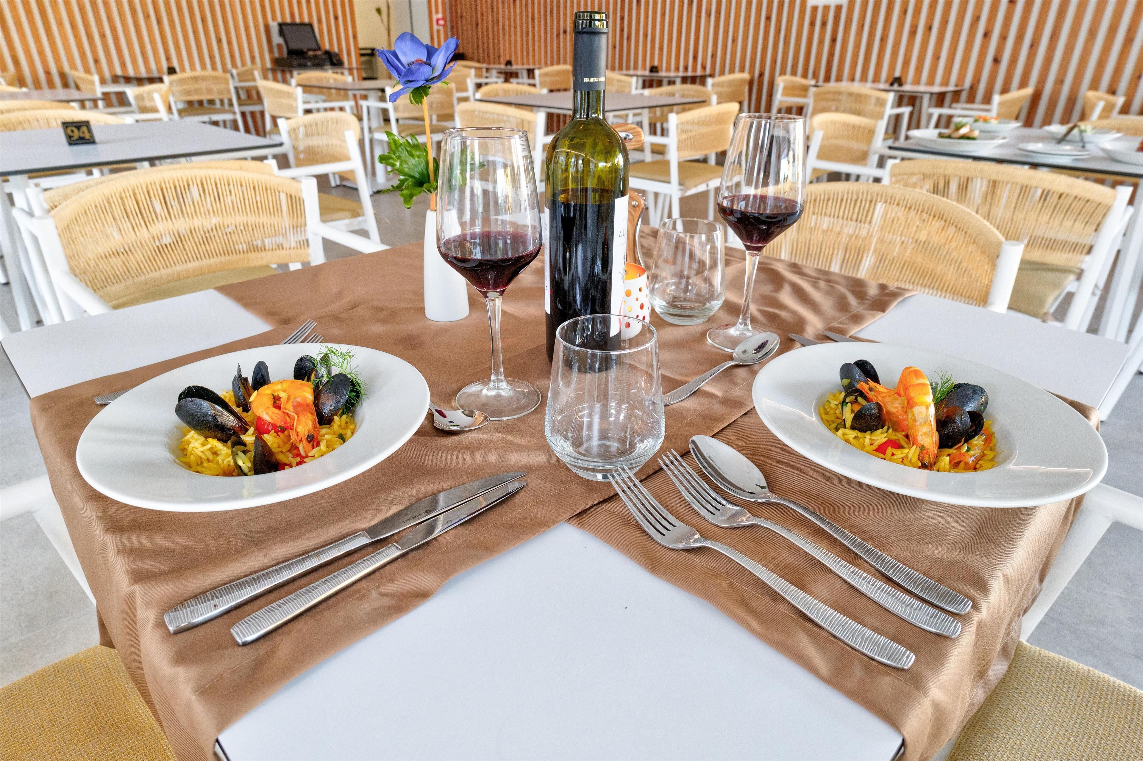 Ein Esstisch ist mit zwei Fischplatten, Weingläsern und Besteck gedeckt.