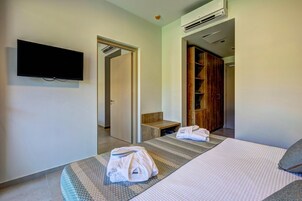 Ett hotellrum med en säng, en tv som är monterad på väggen, en garderob i trä och ett badrum som syns genom en öppen dörr.