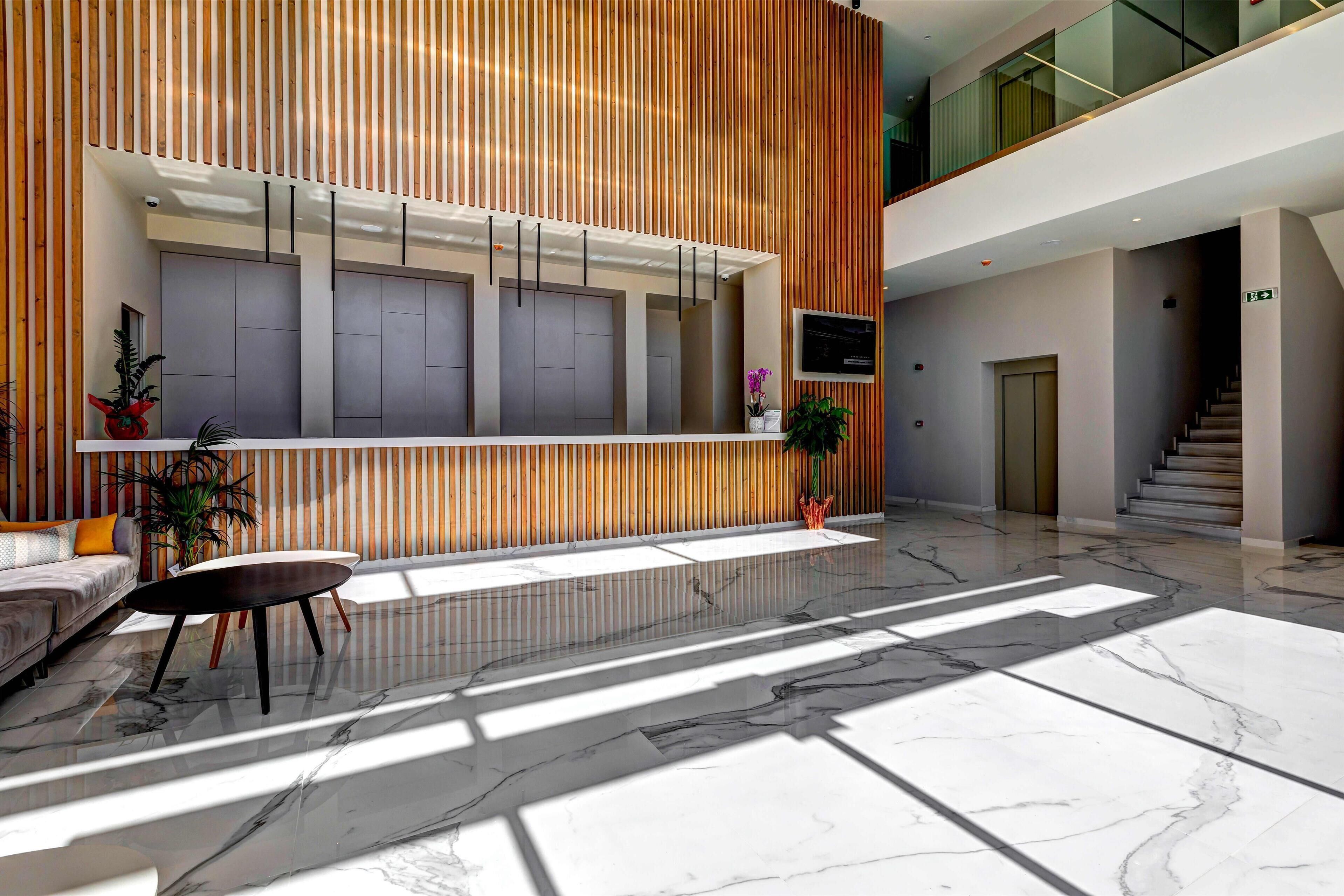 Una hall moderna con una reception, una zona salotto e una scala.
