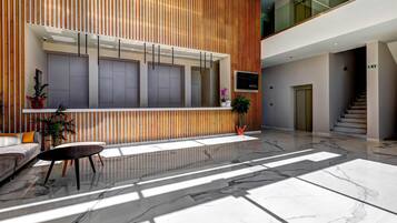 Una hall moderna con una reception, una zona salotto e una scala.