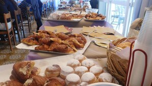 Una mesa de buffet con diversos pasteles, incluyendo croissants y rosquillas azucaradas, y un plato con el logotipo del hotel.