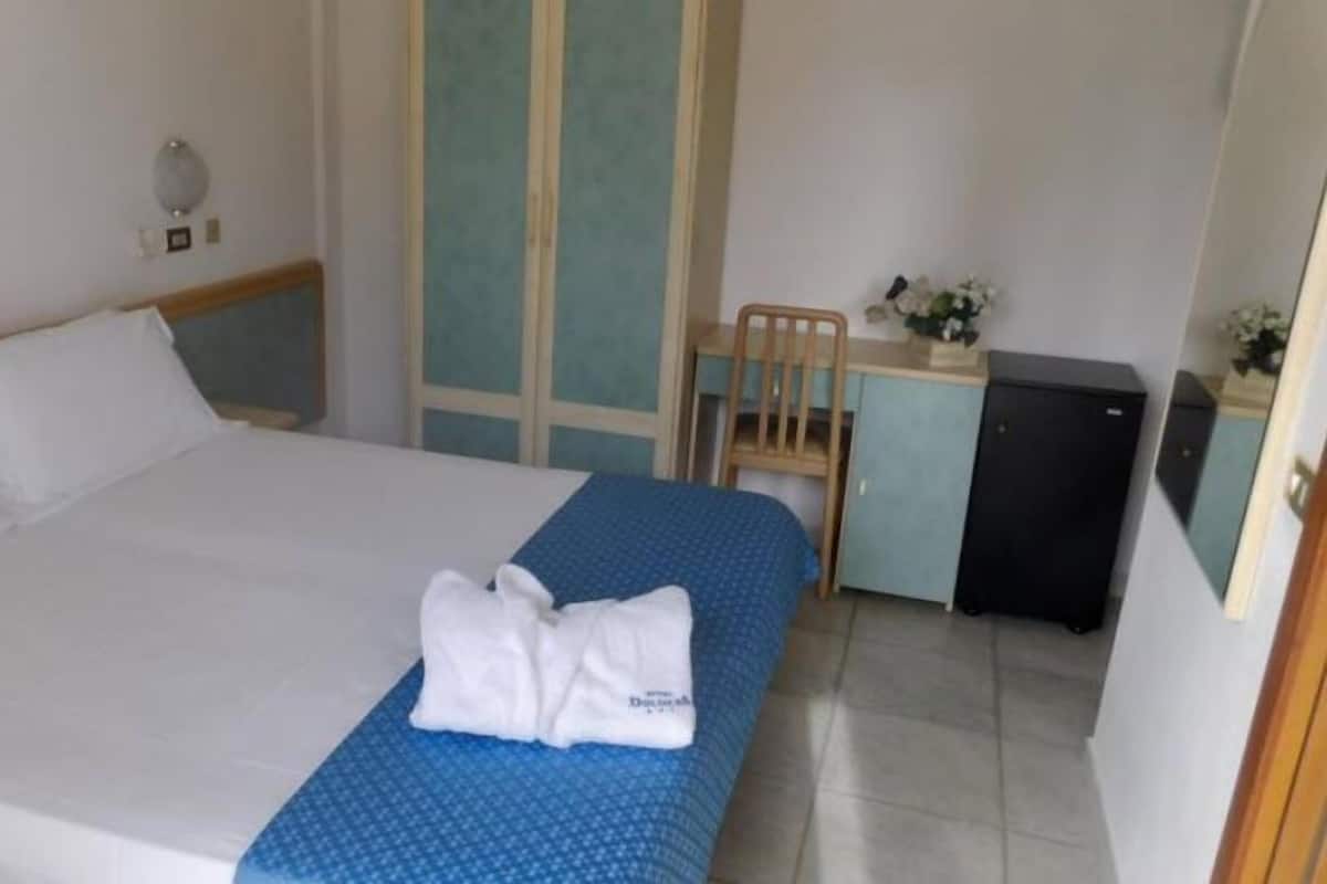 A hotel room with a bed, a desk, and a chair.
