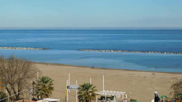 Una playa con vista despejada al mar, una orilla arenosa y un cartel que indica un lugar.