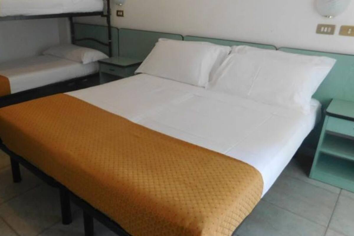 A single bed with a brown blanket, a bedside table, and a nightstand.