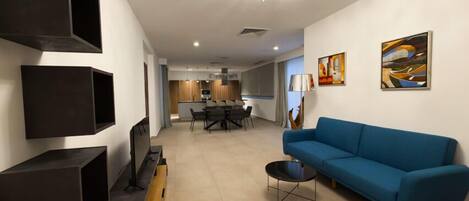 A modern living room with a blue sofa, a TV, and a chandelier.