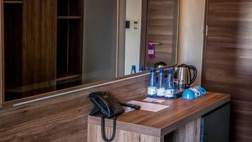 Un mostrador de recepción de hotel con un teléfono, botellas de agua y equipo para preparar café.