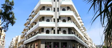 Um edifício moderno de vários andares com design arquitetônico singular, com varandas e um átrio central.