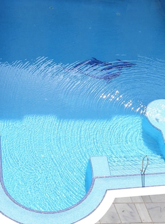 Una piscina techada, una piscina al aire libre, sombrillas