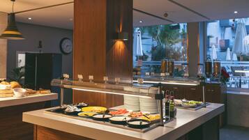 A buffet area with various food options, a clock on the wall, and a view of the outside through large windows.