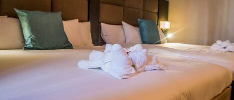 A hotel room with a large bed, multiple pillows, and a neatly folded towel on the bed.
