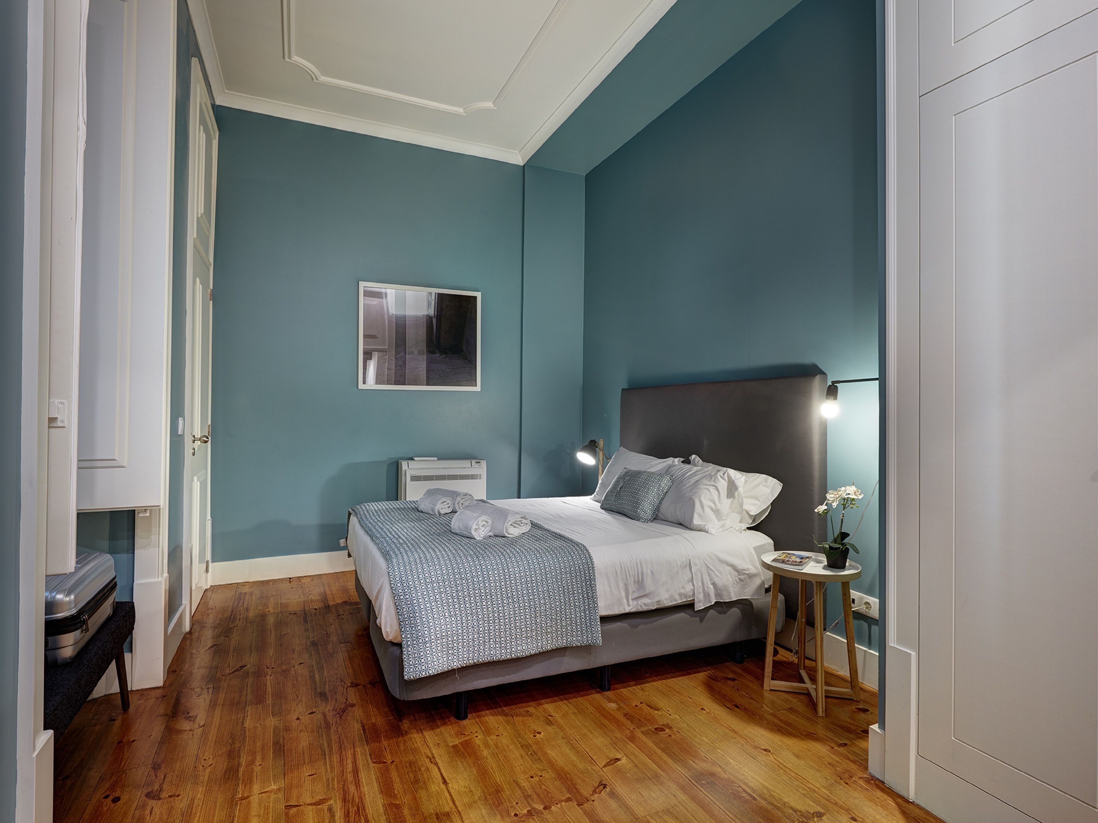 A bedroom with a bed, bedside table, and a wall-mounted picture.