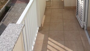 A narrow balcony with a white railing, a small table, and a chair. - Apartments Miki Pag (Pag)