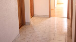 A hallway with tiled flooring and wooden doors, leading to another room. - Apartments Miki Pag (Pag)