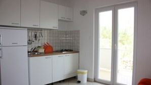 A kitchen with white cabinets, a Koncar refrigerator, a sink, and a stove. There is a trash bin with yellow tape. - Apartments Miki Pag (Pag)