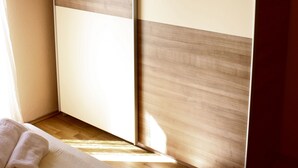 A bedroom with a bed, a wardrobe, and a window allowing natural light. - Apartments Miki Pag (Pag)