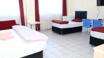 A hotel room with two beds, a desk, a chair, a TV, and a small cabinet.