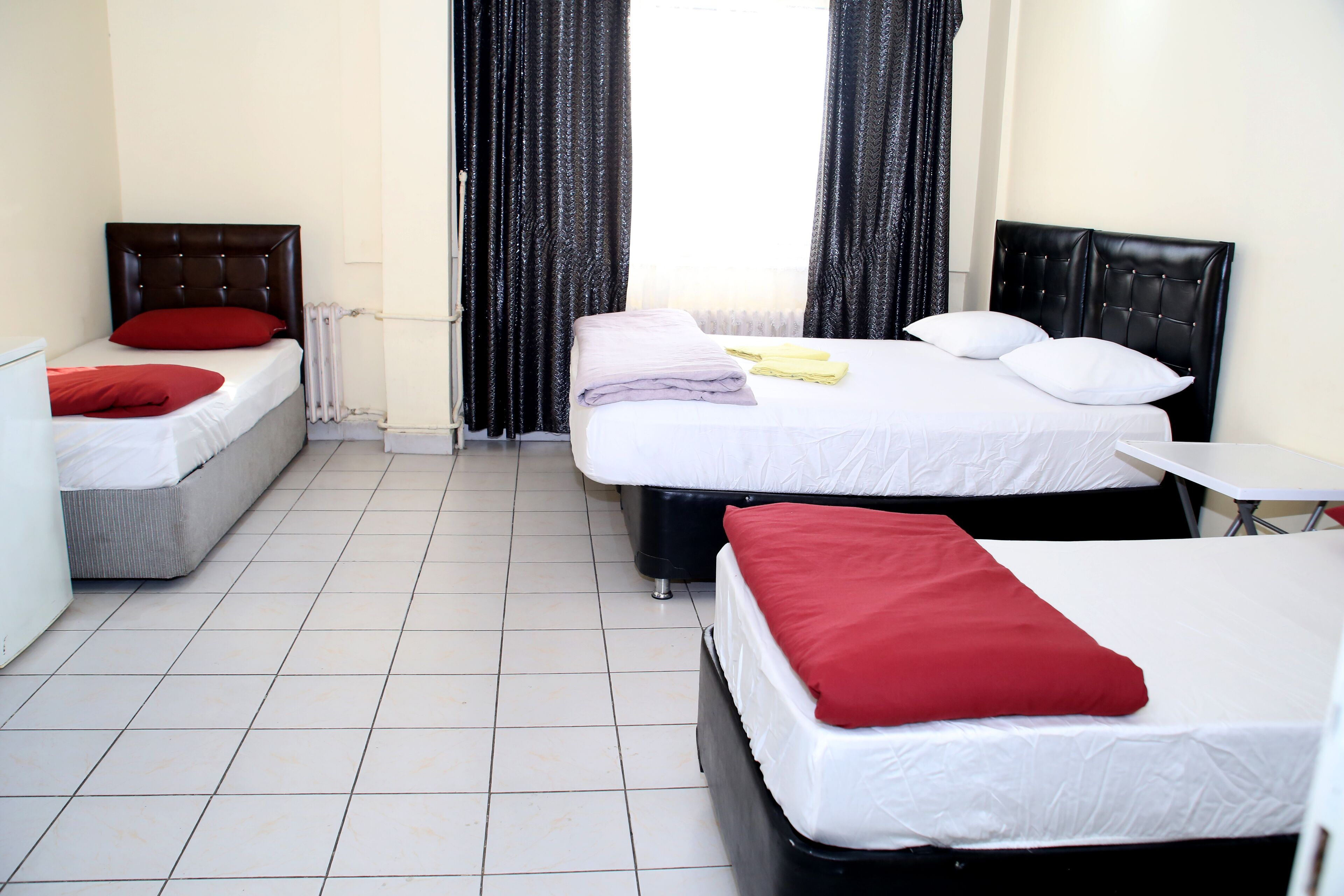 Een hotelkamer met twee bedden, een tafeltje en een radiator.