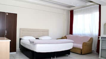 Une chambre à coucher comprenant un lit, un canapé, un meuble pour la télévision et une armoire.