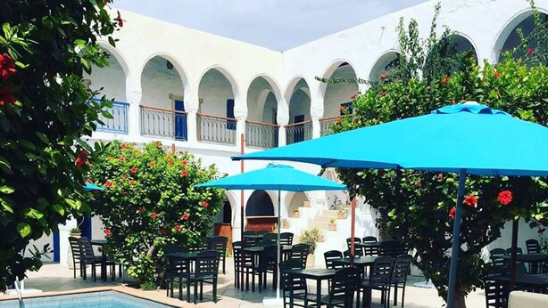 A poolside area with a pool, lounge chairs, and umbrellas. - Hotel Arisha (Houmt Souk)