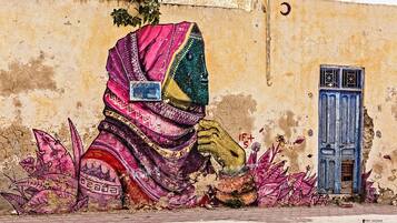 A mural of a woman in traditional attire on a wall with a blue door.