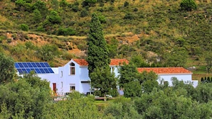A white building with a red-tiled roof, solar panels, and surrounded by greenery. - La Fuente Retreat (Lecrin)