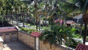 A courtyard with a stone wall, palm trees, and a tiled roof structure. - Alameda dos Eucalipitos (Rio de Janeiro)