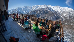 Zona esterna con tavoli e sedie coperta di neve, con vista su montagne innevate.