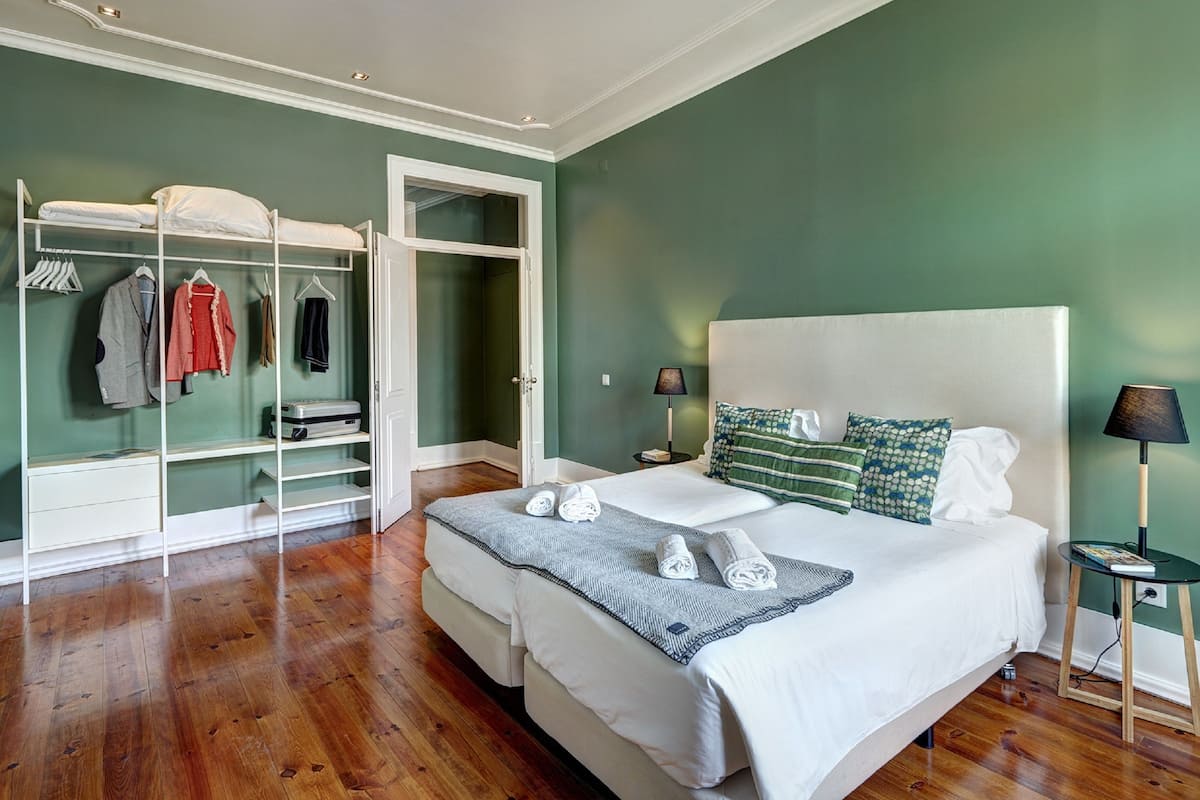 A bedroom with a large bed, a wardrobe, and a nightstand with a lamp.